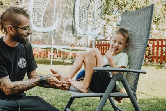 Playful interaction between a father and son in a sunny backyard setting.