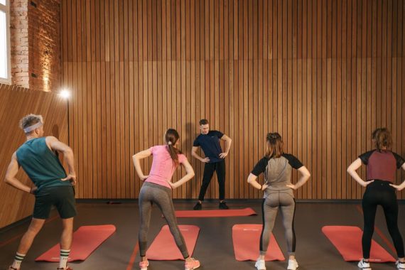 People stretching on yoga mats during a fitness class indoors.